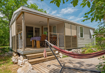 Mobile home at Midi Pyrénées lodge, featuring a covered terrace, dining table, chairs, and hammock.