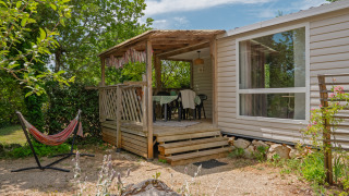 Mobile home Loggia: Acogedora terraza con mesa, sillas y hamaca, rodeada de vegetación y tranquilidad.