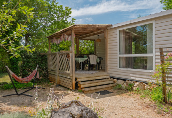Mobile home Loggia: Cozy porch with table and chairs, hammock, surrounded by trees and lush greenery.