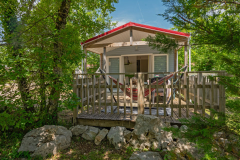 Mobile home Aveyron lodge with wooden deck, hammock, forest surroundings, and relaxing natural view.