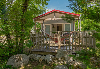 Mobile home Aveyron lodge with wooden deck, hammock, forest surroundings, and relaxing natural view.
