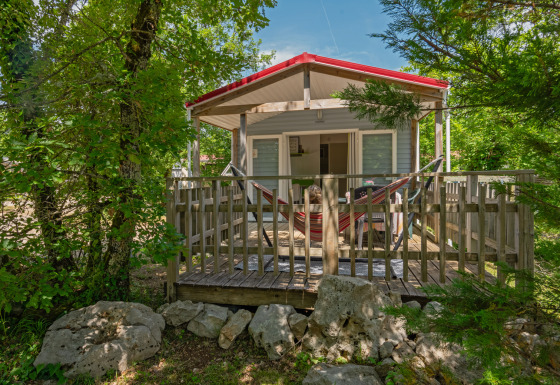 Casa móvil Aveyron con terraza de madera, hamaca y naturaleza verde alrededor del alojamiento tranquilo.