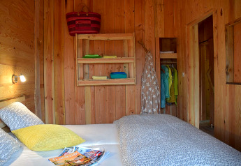 Camera da letto nello Chalet al Campeggio Les 3 Cantons, Francia, con pareti in legno e biancheria colorata.