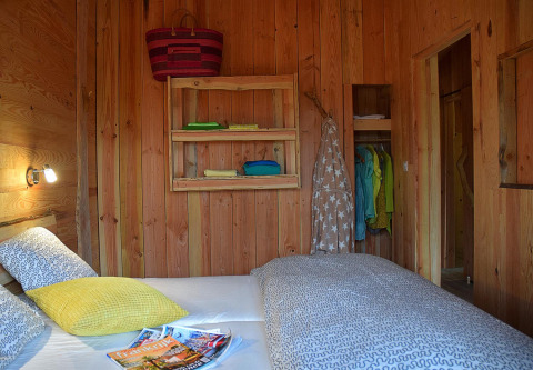 Camera da letto nello Chalet al Campeggio Les 3 Cantons, Francia, con pareti in legno e biancheria colorata.