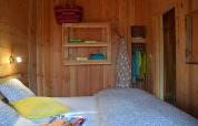 Camera da letto nello Chalet al Campeggio Les 3 Cantons, Francia, con pareti in legno e biancheria colorata.