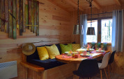 Accogliente angolo pranzo in chalet di legno al campeggio Les 3 Cantons, Francia, con cuscini e stoviglie colorati.