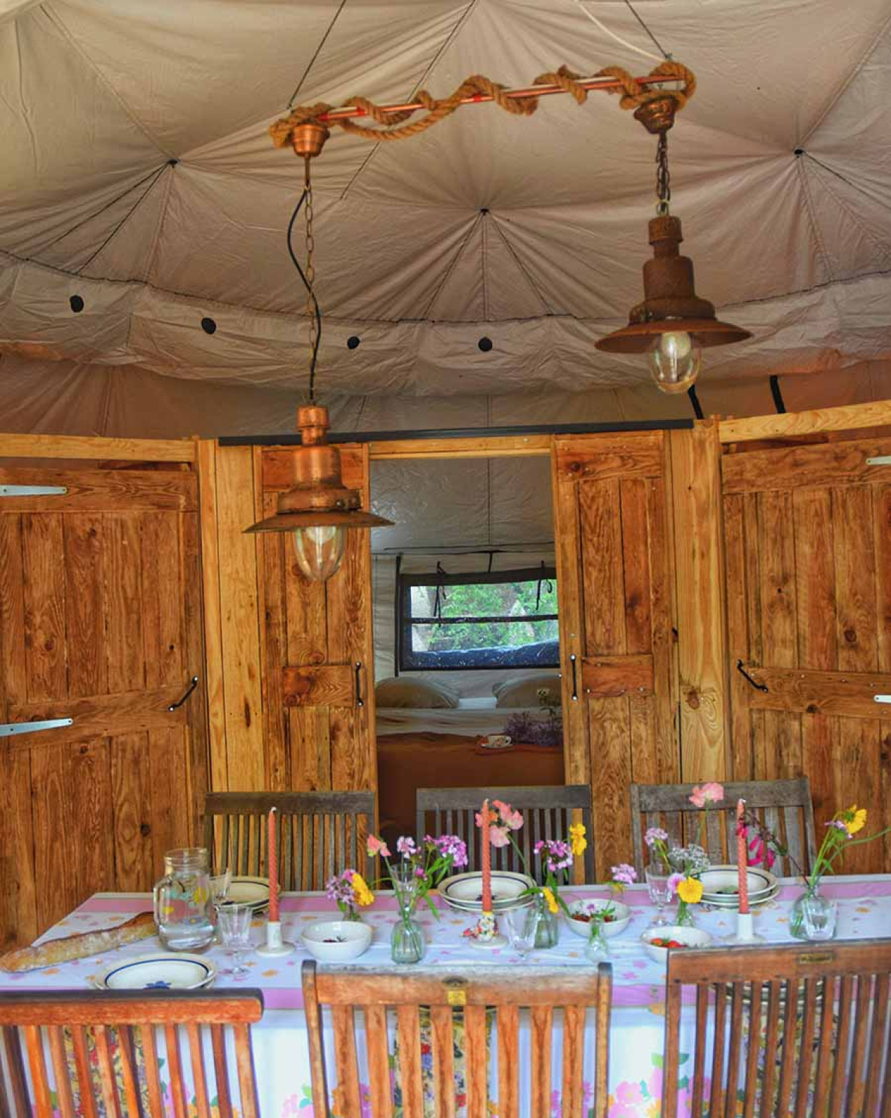Interieur van de safaritent Dôme op Camping Les 3 Cantons in Frankrijk, met gedekte tafel en slaapkamer.