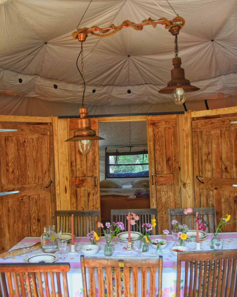 Interno della tenda safari Dôme al campeggio Les 3 Cantons in Francia con tavola apparecchiata e camera.