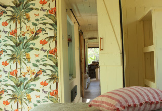 Interno della Lijn 3C cozy school bus al campeggio Les 3 Cantons in Francia, con carta da parati floreale