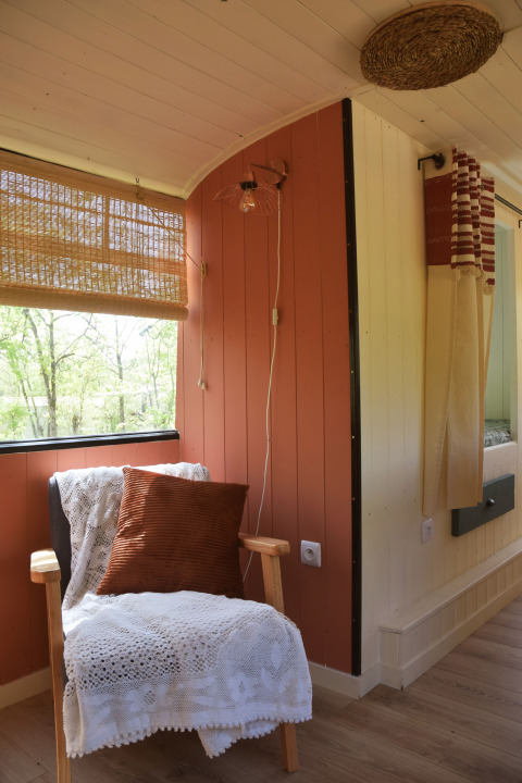 Gemütliche Leseecke im Lijn 3C Schulbus-Lodge mit Sessel, Kissen und Decke, Les 3 Cantons, Frankreich.