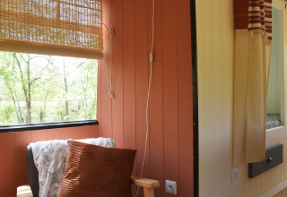 Gemütliche Leseecke im Lijn 3C Schulbus-Lodge mit Sessel, Kissen und Decke, Les 3 Cantons, Frankreich.