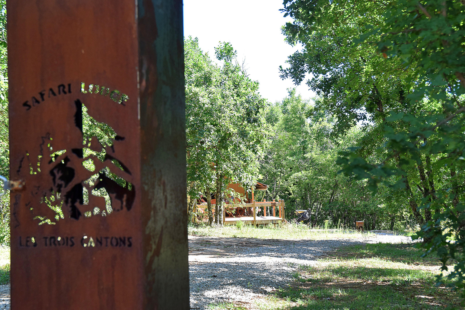 Safaritent op Camping Les 3 Cantons in Frankrijk, omringd door bomen en natuur, gezien vanaf de ingang.