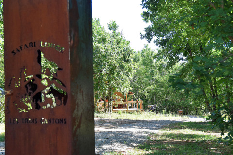 Safaritent op Camping Les 3 Cantons in Frankrijk, omringd door bomen en natuur, gezien vanaf de ingang.