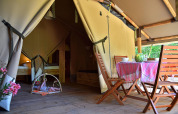 Intérieur d'une tente safari au Camping Les 3 Cantons en France, avec coin repas et un bébé au sol.
