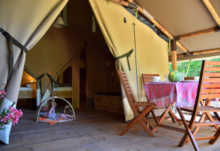 Binnenaanzicht van een safaritent op Camping Les 3 Cantons in Frankrijk, met eethoek en een baby.