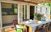 Zona pranzo all'aperto sulla terrazza di Starcaravan Lavaurette al campeggio Les 3 Cantons, Francia.