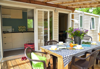 Espace repas extérieur sur la terrasse du Starcaravan Lavaurette au camping Les 3 Cantons, France.