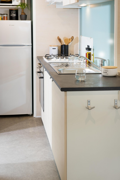 Modern kitchenette inside Starcaravan Lavaurette at Campsite Les 3 Cantons, France, with stove and sink.