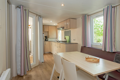Modern mobile home interior at Midi Pyrénées, Campsite Les 3 Cantons, with kitchen, dining area and windows.