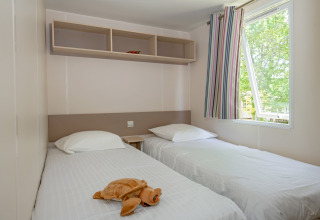 Camera con due letti singoli, lenzuola bianche, peluche e finestra al Mobile home «Midi Pyrénées».