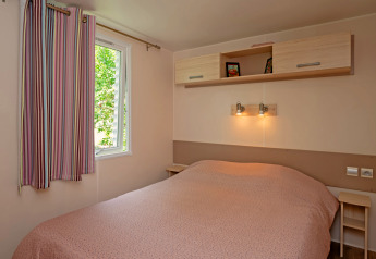 Slaapkamer van Mobile home «Midi Pyrénées» op camping Les 3 Cantons in Frankrijk, met tweepersoonsbed.