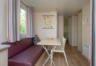 Bright, cozy living and dining area in Mobile home «Midi Pyrénées» at Campsite Les 3 Cantons, France.