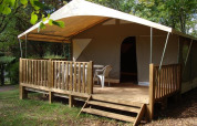 Tenda safari Lodge Canada Comfort al campeggio La Grande Véyière in Francia, con terrazza in legno e sedie.
