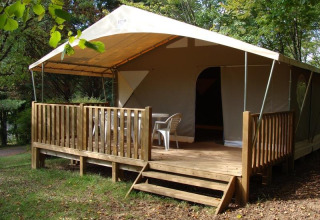 Safari tent Lodge Canada Comfort op Camping La Grande Véyière in Frankrijk met houten terras en stoelen.