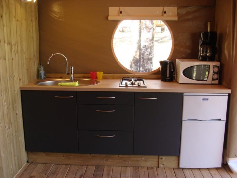 Cucina moderna in tenda safari a Lodge Canada Comfort in Francia con lavello, fornello e finestra rotonda.