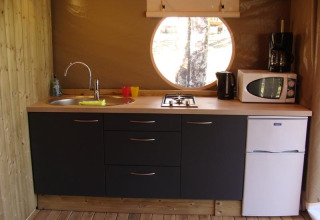 Moderne safaritentkeuken in Lodge Canada Comfort, Frankrijk, met spoelbak, fornuis en rond raam.