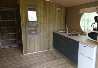 Vue intérieure de la tente safari Lodge «Canada Comfort» avec kitchenette au camping La Grande Véyière, France.