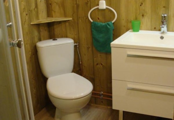 Salle de bain en bois avec toilettes, lavabo, miroir et douche au Lodge Canada Comfort à La Grande Véyière.