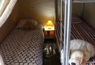Interno della tenda safari Lodge Canada Comfort con letto singolo, letto a castello, comodino e lampada.
