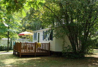 Mobile home Comfort en el camping La Grande Véyière en Francia, rodeado de árboles y vegetación.