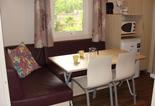 Essbereich mit Tisch, Stühlen und Eckbank im Mobile Home Comfort auf dem Campingplatz La Grande Véyière, Frankreich.