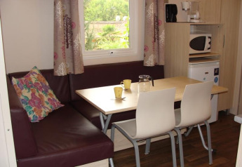Dining area with table, chairs and corner sofa in Mobile home Comfort at Campsite La Grande Véyière, France.
