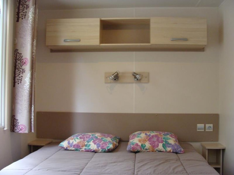 Chambre du mobil-home Comfort au camping La Grande Véyière en France avec lit double et rangements.