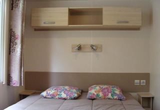 Chambre du mobil-home Comfort au camping La Grande Véyière en France avec lit double et rangements.