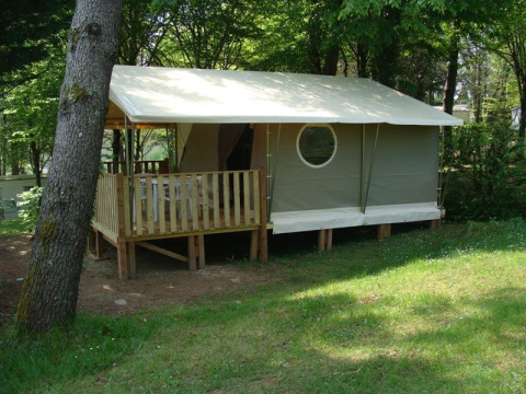 Safari-tent Lodge ‘Canada Classic’ met houten terras bij La Grande Véyière in Frankrijk, omgeven door bomen.