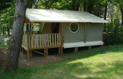 Safari-tent Lodge ‘Canada Classic’ met houten terras bij La Grande Véyière in Frankrijk, omgeven door bomen.