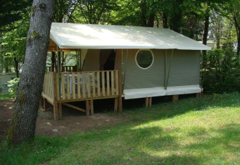 Tenda safari Lodge «Canada Classic» con veranda in legno al Campeggio La Grande Véyière in Francia, tra gli alberi.