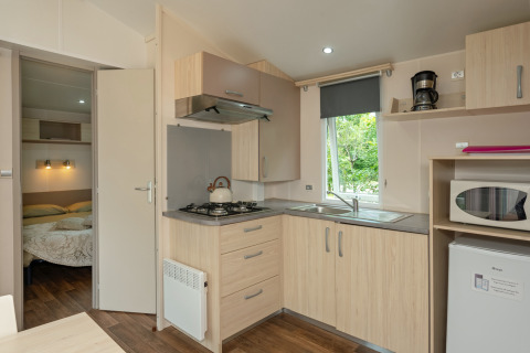 Modern kitchenette and bedroom in a Mobile home Loggia at Campsite Les 3 Cantons, France.