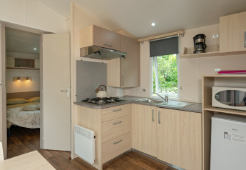Modern kitchenette and bedroom in a Mobile home Loggia at Campsite Les 3 Cantons, France.