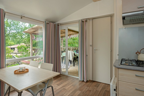 Indvendig udsigt fra Mobile home «Loggia» på Camping Les 3 Cantons i Frankrig, med spisebord og terrasse.