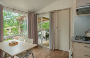 Indvendig udsigt fra Mobile home «Loggia» på Camping Les 3 Cantons i Frankrig, med spisebord og terrasse.