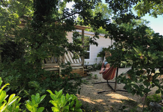 Acogible casa móvil en el camping Les 3 Cantons, Francia, con una persona relajándose en una hamaca al aire libre.