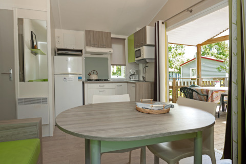 Modern kitchen and dining area inside Mobile home “Aveyron” with terrace view at Les 3 Cantons campsite.