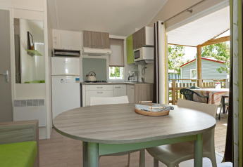 Modern kitchen and dining area inside Mobile home “Aveyron” with terrace view at Les 3 Cantons campsite.