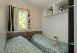 Chambre du Mobil-home «Aveyron» au camping Les 3 Cantons en France, avec deux lits simples et une déco chaleureuse.