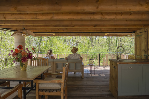 Mensen ontspannen in de boomhut Duiventoren op Camping Les 3 Cantons in Frankrijk, met boszicht.